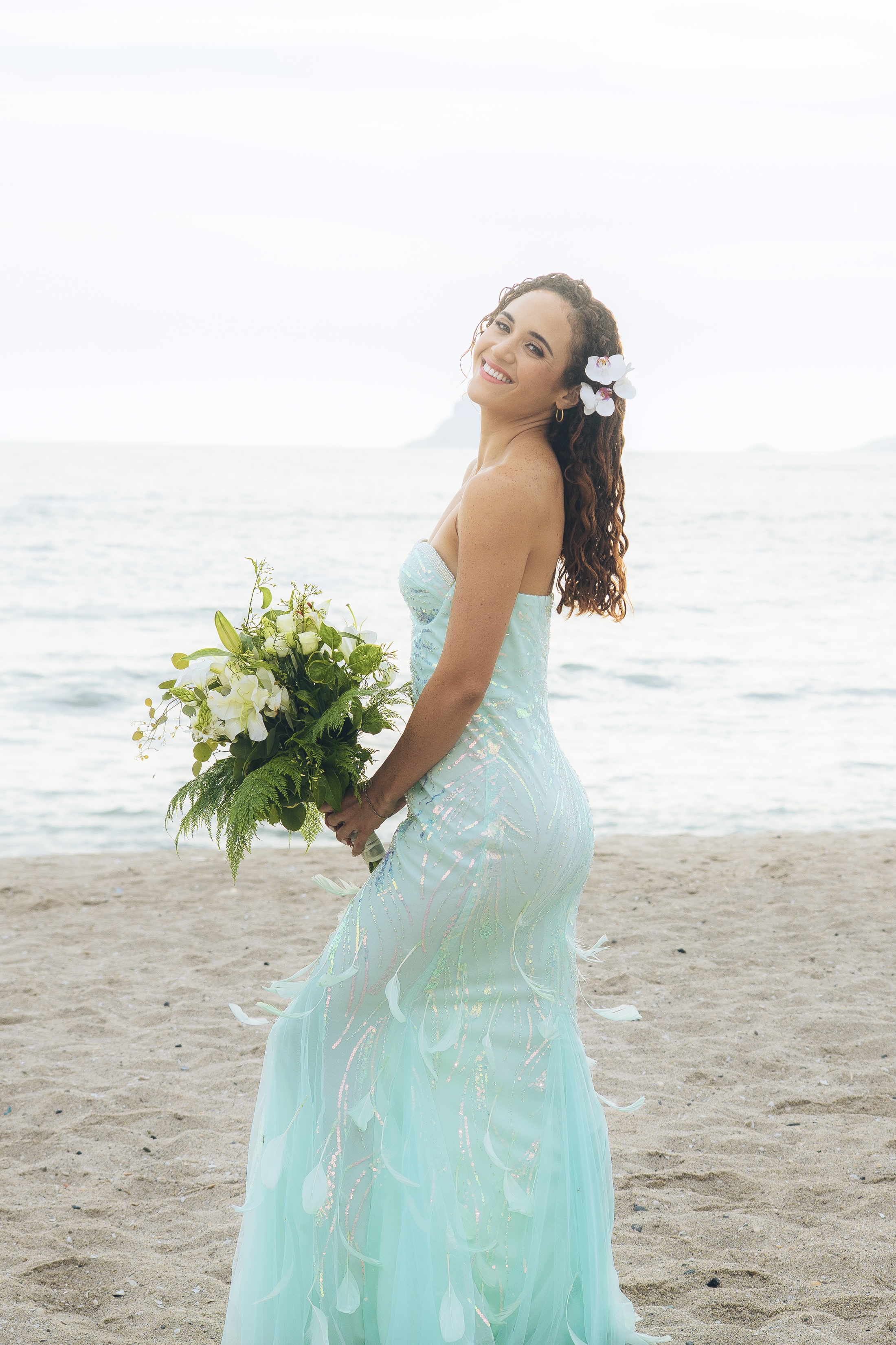 Vestido aqua bordado con pedrería y lentejuelas que reflejan la luz con suavidad iridiscente.
El escote strapless se realza con un bordado de perlas que abraza el pecho con dulzura. La falda, con godets, abre su vuelo con naturalidad y culmina en una base de plumas ligeras que acompañan el andar como espuma.
Inspirado en la belleza silenciosa de las sirenas, para habitarte con encanto y presencia.

· Tul bordado con perlas, lentejuelas y pedrería + acabado en plumas
· Se adapta de S a M
· Pieza única – venta o alquiler
